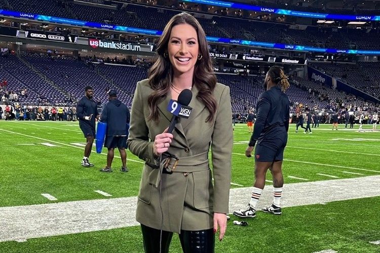 Reporter holding a WGN microphone on a football field at Lumen Field