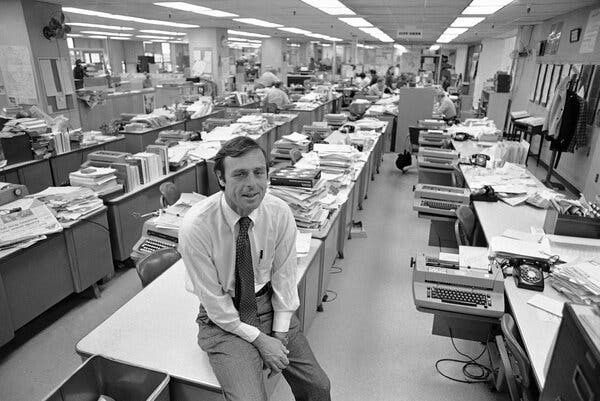 Black-and-white newsroom with an editor seated among crowded desks